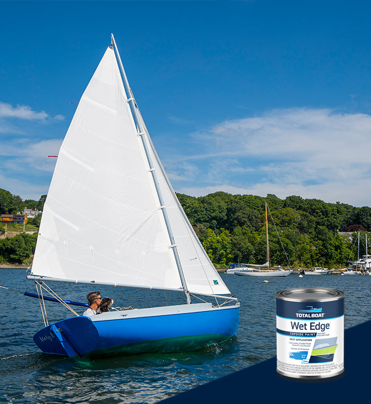 A sailor/do-it-yourselfer and his dog out on the bay in their Levant 15 sailboat, which is sporting a shiny, TotalBoat Wet Edge Topsdie Paint job in Largo Blue.